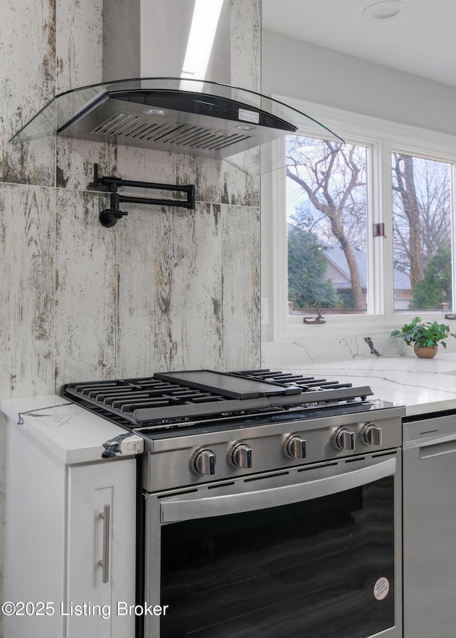 kitchen with white cabinetry, stainless steel range, light stone countertops, and island exhaust hood