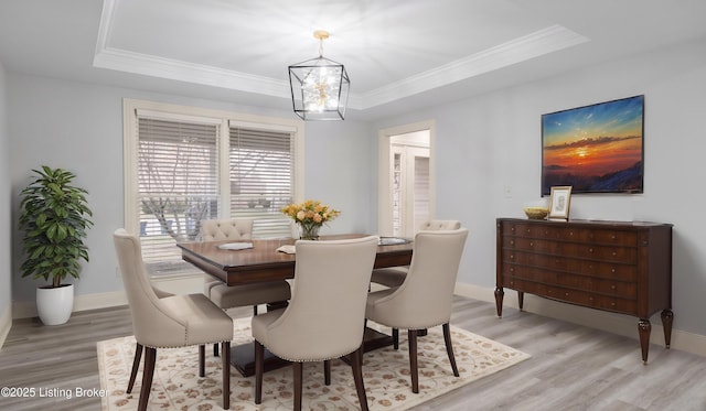 dining area featuring hardwood / wood-style flooring, ornamental molding, a raised ceiling, and a chandelier