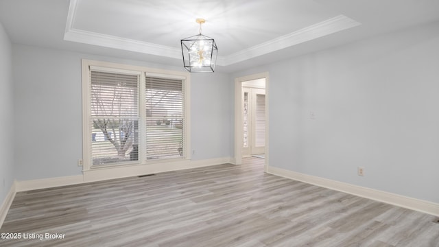 unfurnished room with crown molding, light hardwood / wood-style floors, a chandelier, and a tray ceiling