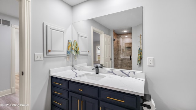 bathroom featuring a shower with door and vanity