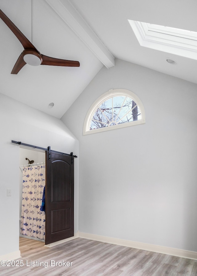 entryway with a barn door, light hardwood / wood-style flooring, and vaulted ceiling with beams