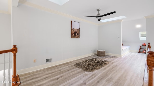 interior space with ornamental molding, light wood-type flooring, and a skylight