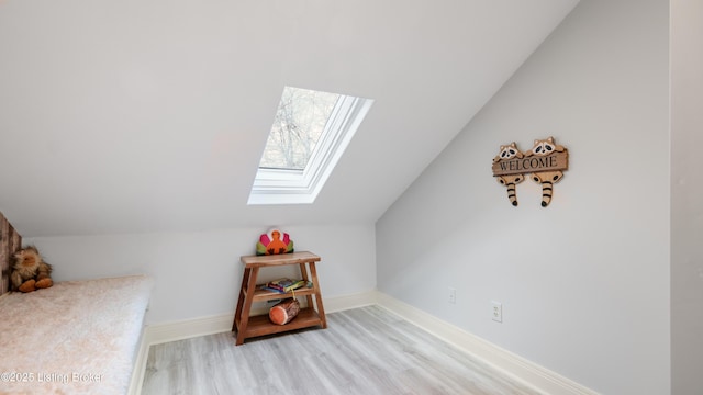 additional living space featuring lofted ceiling with skylight and light hardwood / wood-style floors