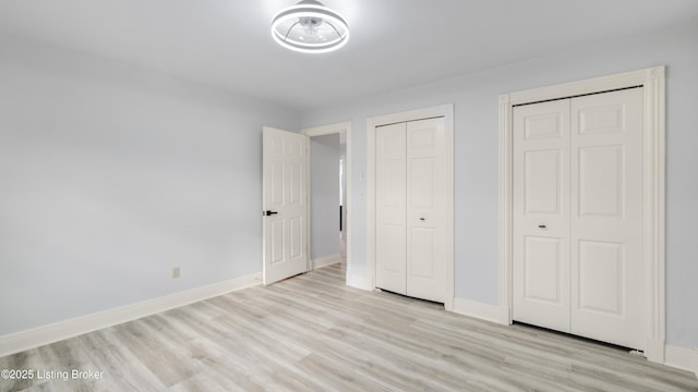 unfurnished bedroom featuring two closets and light hardwood / wood-style flooring