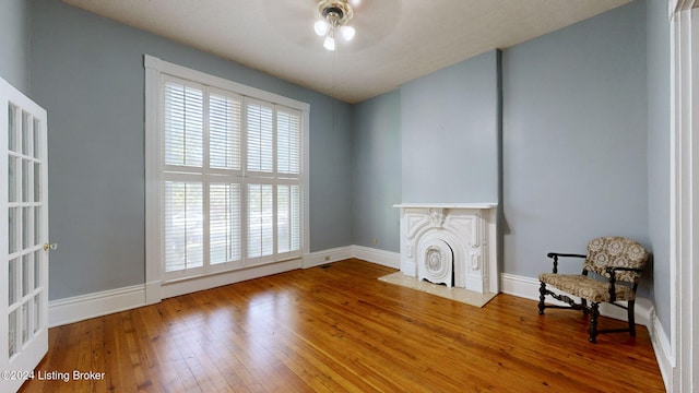 living area featuring hardwood / wood-style floors, ceiling fan, and a fireplace