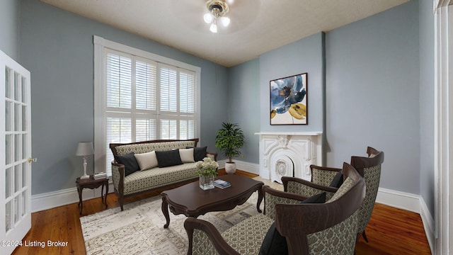 living area with a wealth of natural light, hardwood / wood-style floors, and ceiling fan