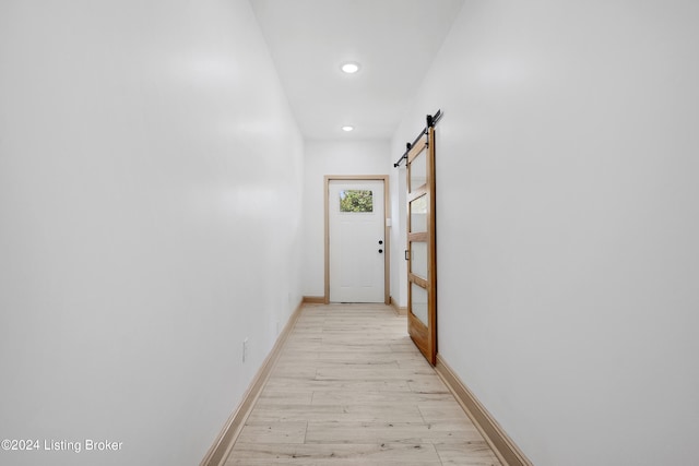 hallway with a barn door and light hardwood / wood-style floors