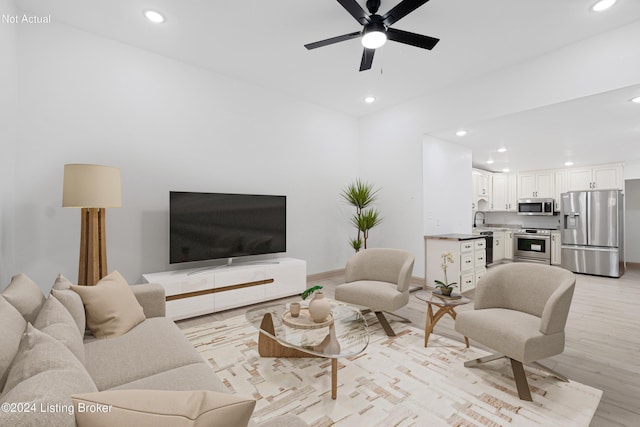 living room featuring light wood-type flooring, ceiling fan, and sink