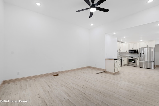 unfurnished living room with ceiling fan, sink, and light hardwood / wood-style floors