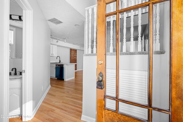 corridor featuring a textured ceiling, light hardwood / wood-style flooring, and sink