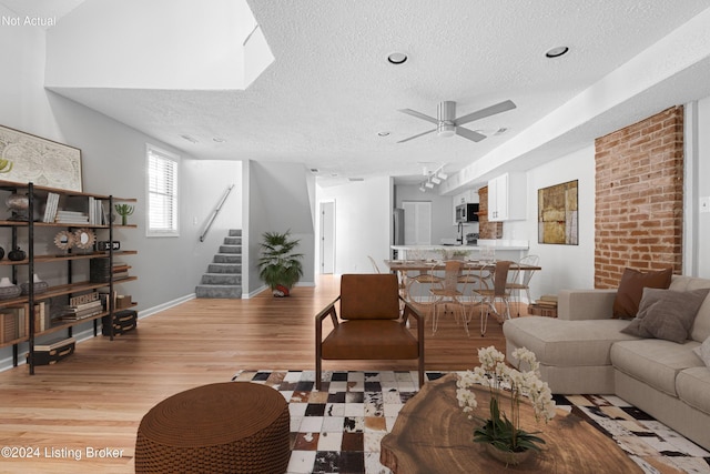 living room featuring light wood-type flooring, a textured ceiling, and ceiling fan