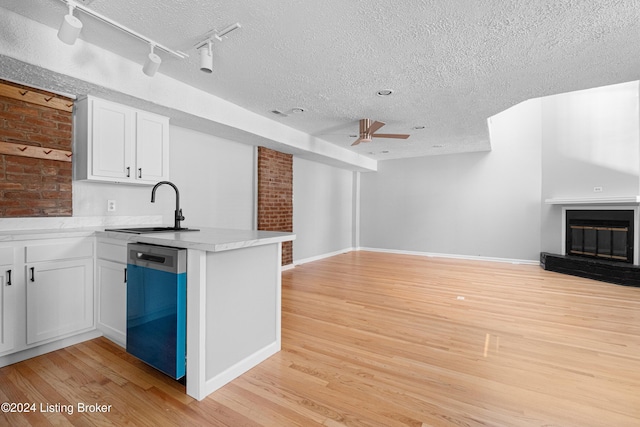 kitchen with stainless steel dishwasher, white cabinets, light wood-type flooring, and sink