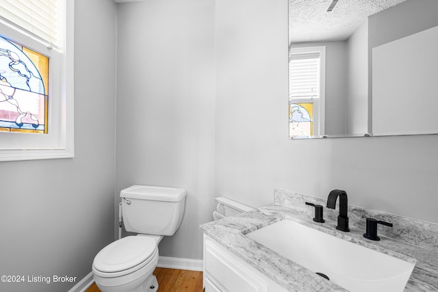 bathroom featuring hardwood / wood-style flooring, vanity, a textured ceiling, and toilet