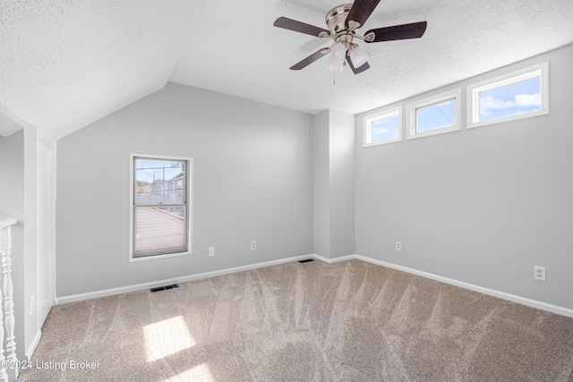 carpeted spare room featuring ceiling fan, a textured ceiling, a wealth of natural light, and vaulted ceiling