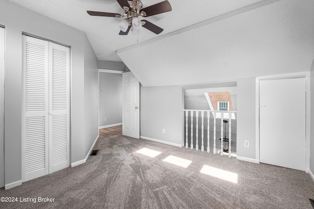 additional living space featuring a textured ceiling, ceiling fan, carpet floors, and vaulted ceiling