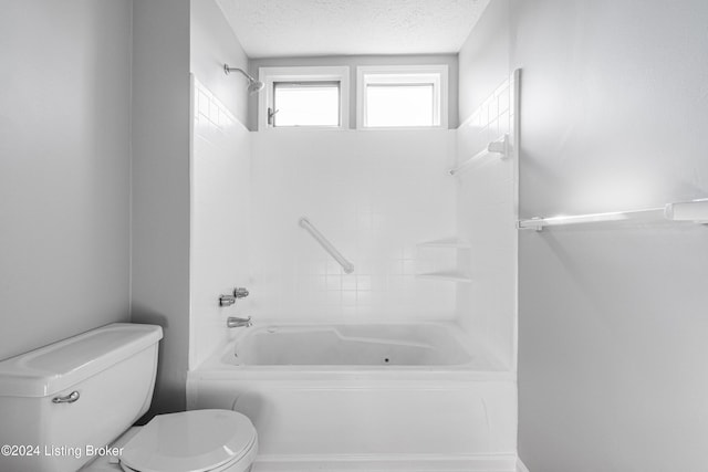 bathroom featuring bathing tub / shower combination, a textured ceiling, and toilet