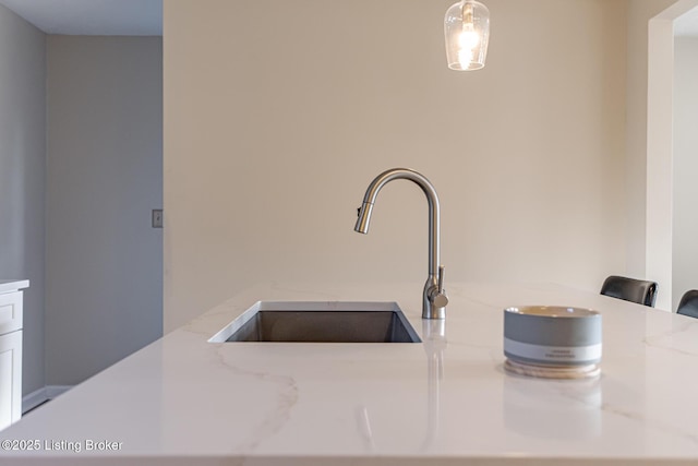 interior details featuring light stone countertops, sink, and hanging light fixtures