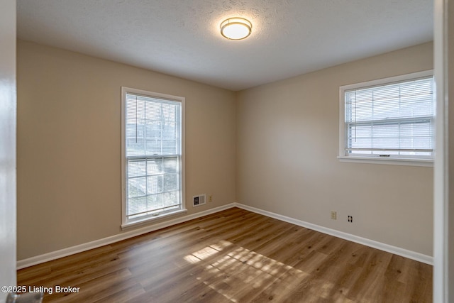 unfurnished room with hardwood / wood-style floors and a textured ceiling