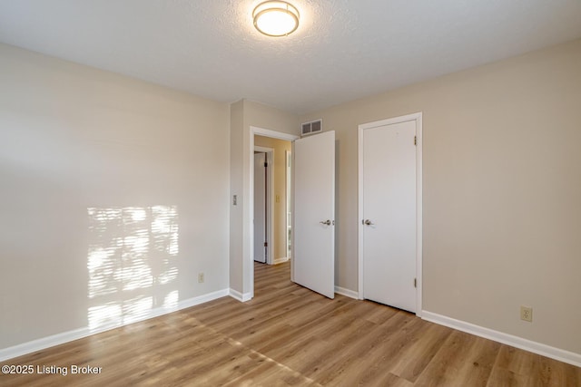 unfurnished bedroom with a closet, light hardwood / wood-style flooring, and a textured ceiling