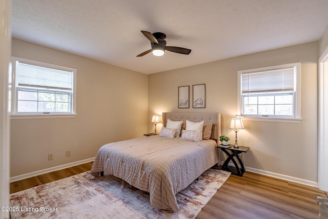 bedroom with ceiling fan, light hardwood / wood-style flooring, and multiple windows