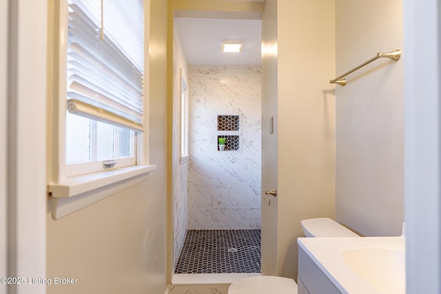 bathroom with a tile shower, vanity, and toilet