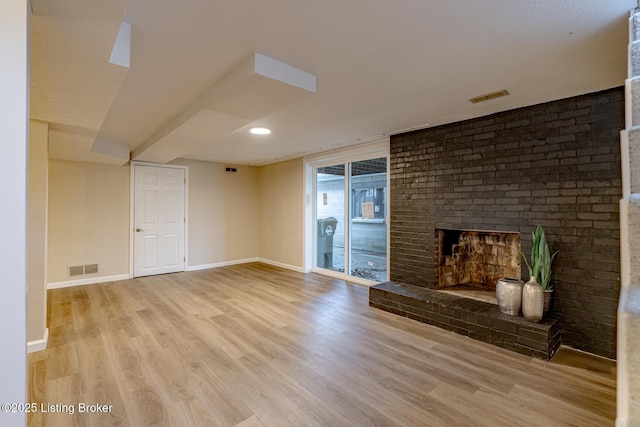 unfurnished living room featuring light hardwood / wood-style flooring and a brick fireplace