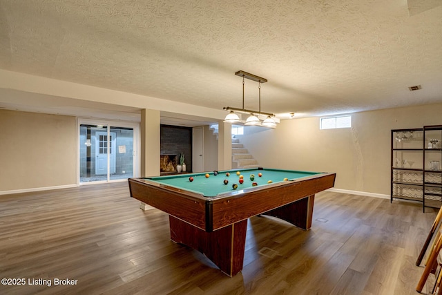 rec room featuring a brick fireplace, hardwood / wood-style flooring, a textured ceiling, and billiards