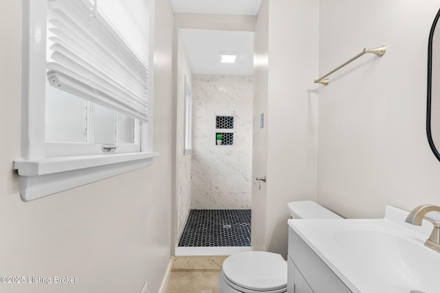 bathroom featuring toilet, vanity, and tiled shower