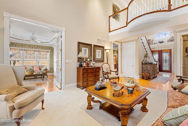 living room with french doors, ceiling fan, crown molding, a high ceiling, and light hardwood / wood-style floors