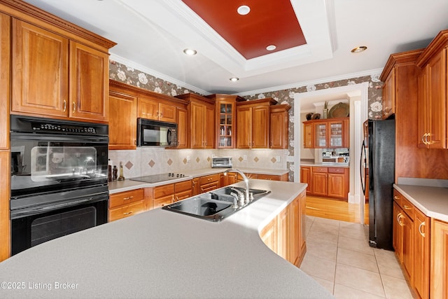 kitchen with tasteful backsplash, a tray ceiling, ornamental molding, and black appliances