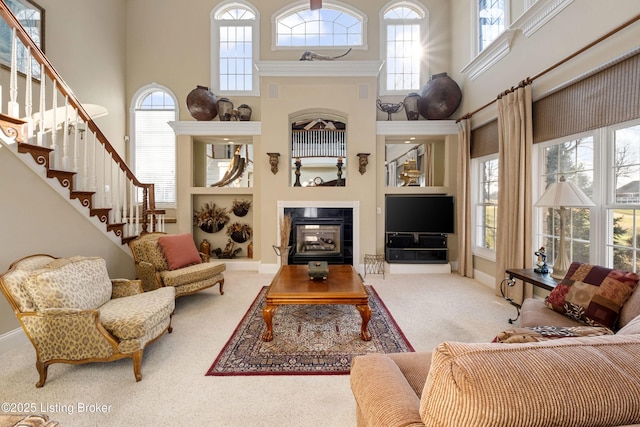 living room with carpet, a towering ceiling, and a tile fireplace