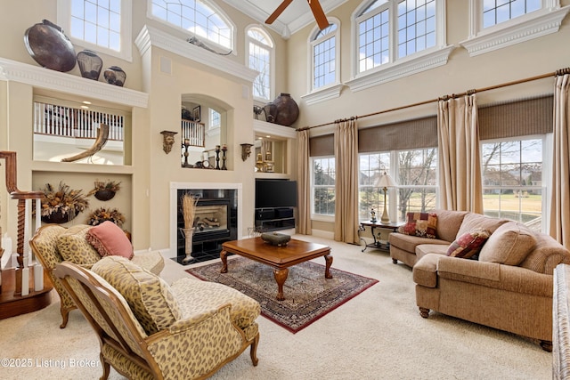 living room with carpet, crown molding, a fireplace, and a high ceiling