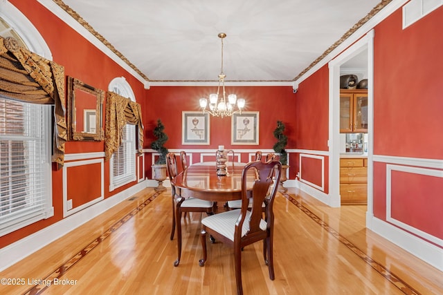 dining area featuring hardwood / wood-style flooring, crown molding, and an inviting chandelier