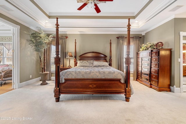 bedroom with ceiling fan, light colored carpet, ornamental molding, and a tray ceiling