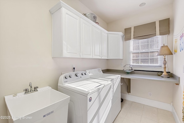 clothes washing area with cabinets, washing machine and dryer, and sink