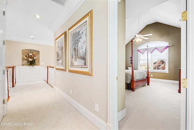 hallway featuring light carpet, vaulted ceiling, and ornamental molding