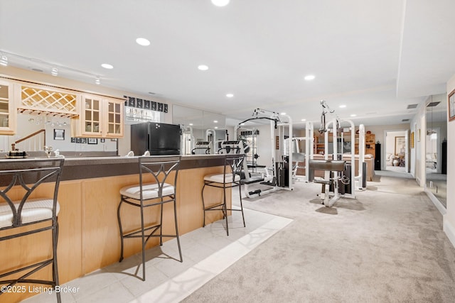 kitchen with black refrigerator, light colored carpet, and a breakfast bar area