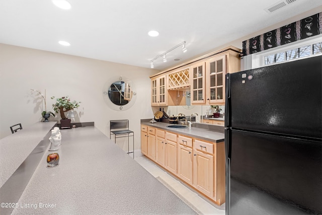 kitchen with rail lighting, black refrigerator, sink, and light brown cabinetry