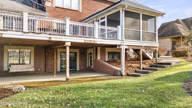 back of property with a yard, a patio area, and a sunroom