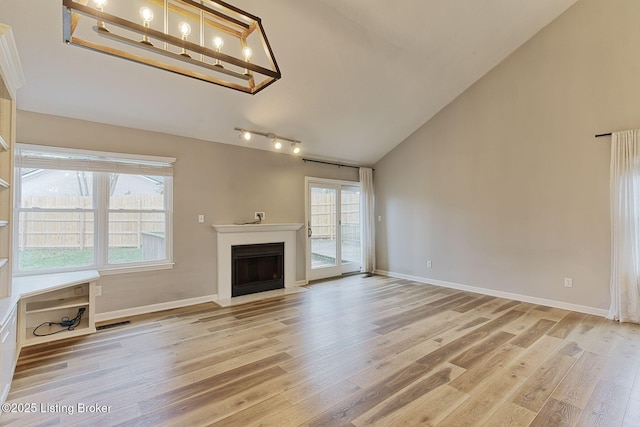 unfurnished living room with light wood-type flooring and high vaulted ceiling