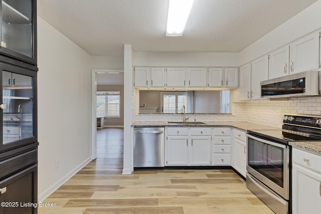 kitchen featuring light stone countertops, sink, white cabinetry, and stainless steel appliances