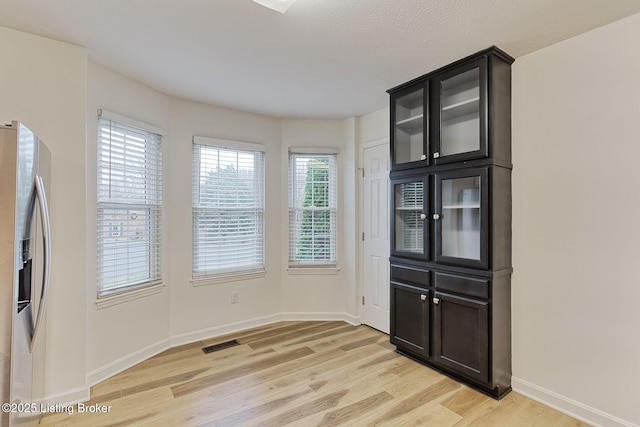 unfurnished dining area featuring a textured ceiling and light hardwood / wood-style flooring