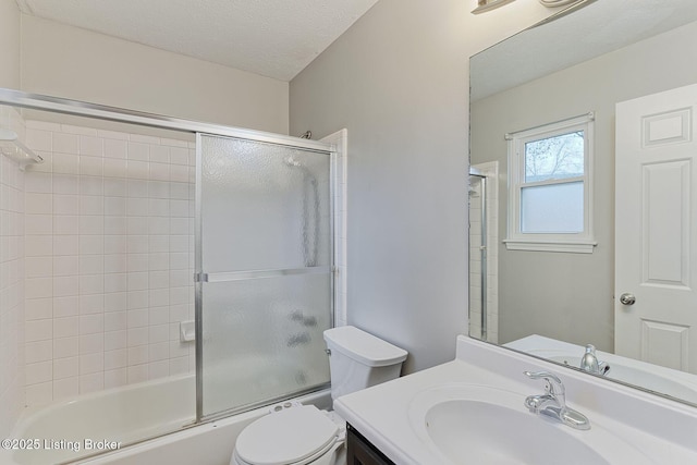 full bathroom with vanity, a textured ceiling, toilet, and enclosed tub / shower combo