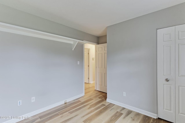 unfurnished bedroom with light wood-type flooring and a closet