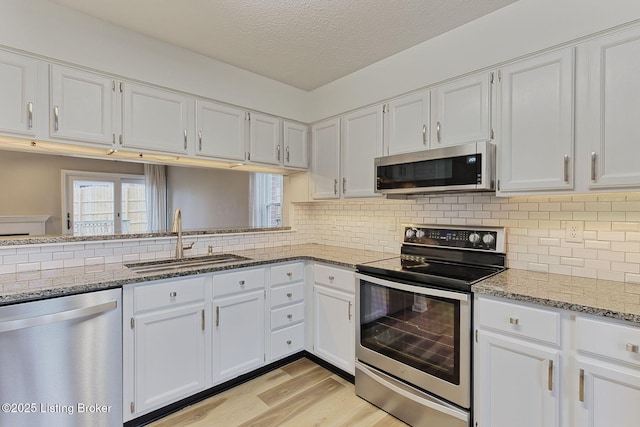 kitchen featuring light stone countertops, sink, white cabinets, and appliances with stainless steel finishes