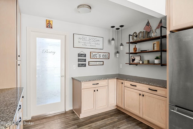 kitchen featuring dark hardwood / wood-style floors, stainless steel fridge, light brown cabinetry, and decorative light fixtures