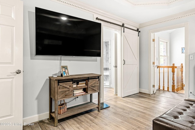 living room featuring a barn door, crown molding, and light hardwood / wood-style flooring