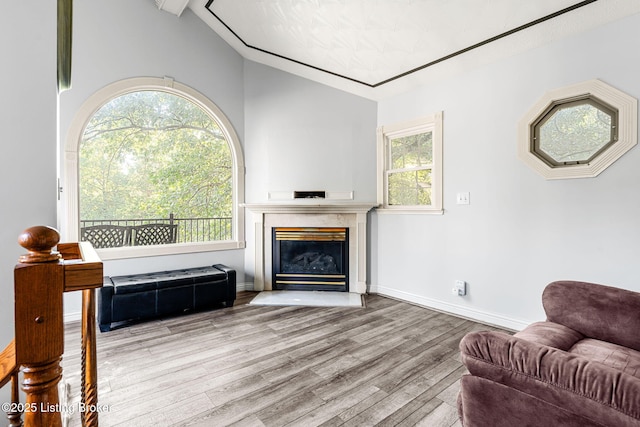 living room with lofted ceiling with beams, a wealth of natural light, and light hardwood / wood-style flooring