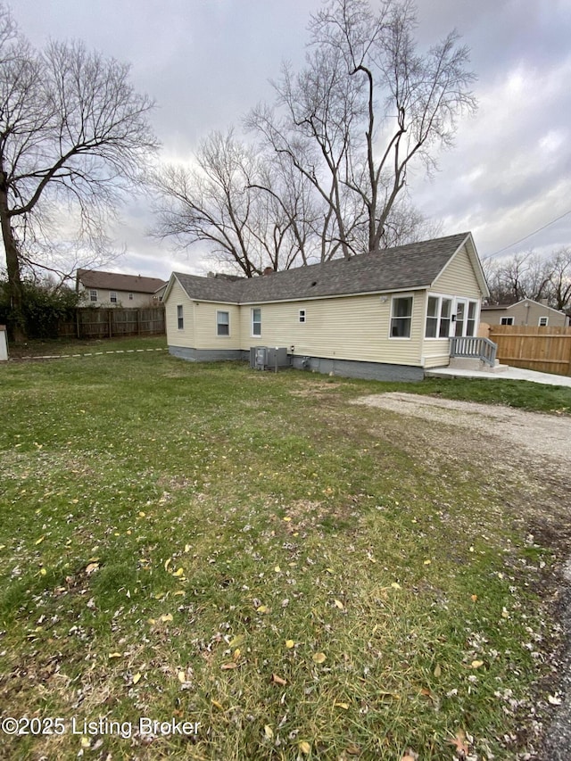 back of property featuring central AC unit and a lawn