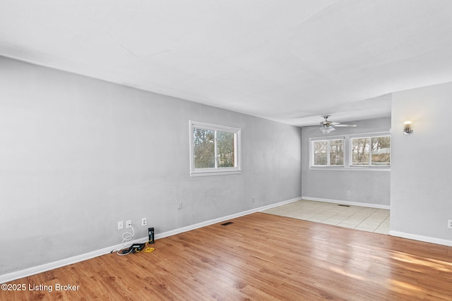 empty room featuring ceiling fan, light hardwood / wood-style flooring, and a wealth of natural light